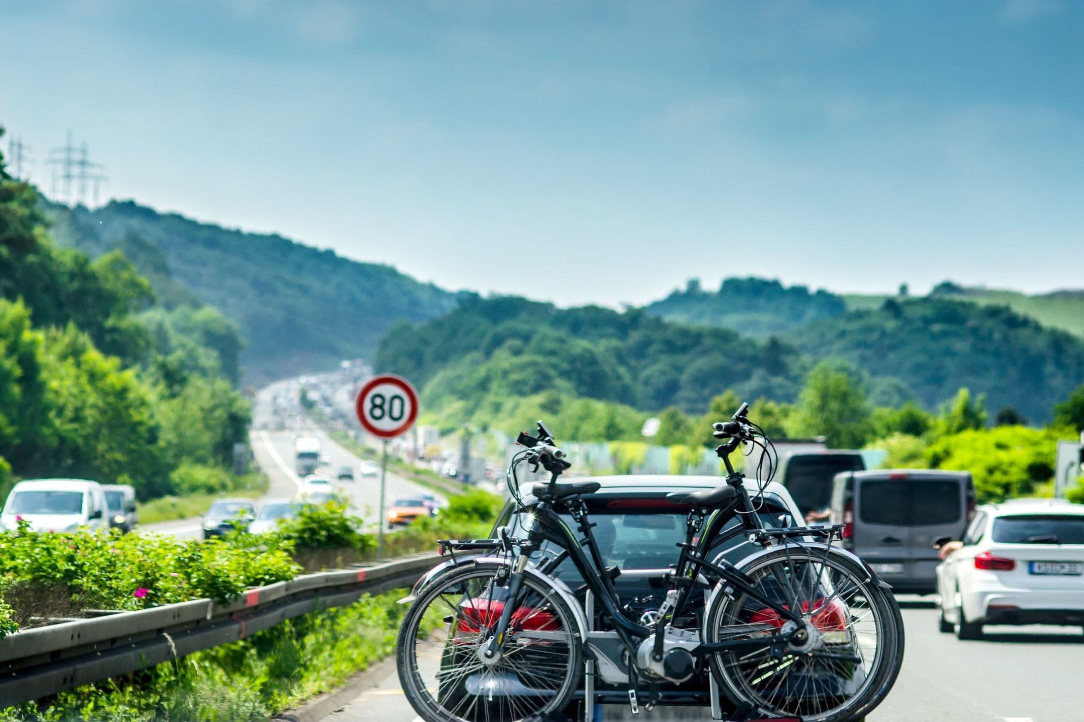 Bil med cykel bagpå på en traffikeret motorvej.