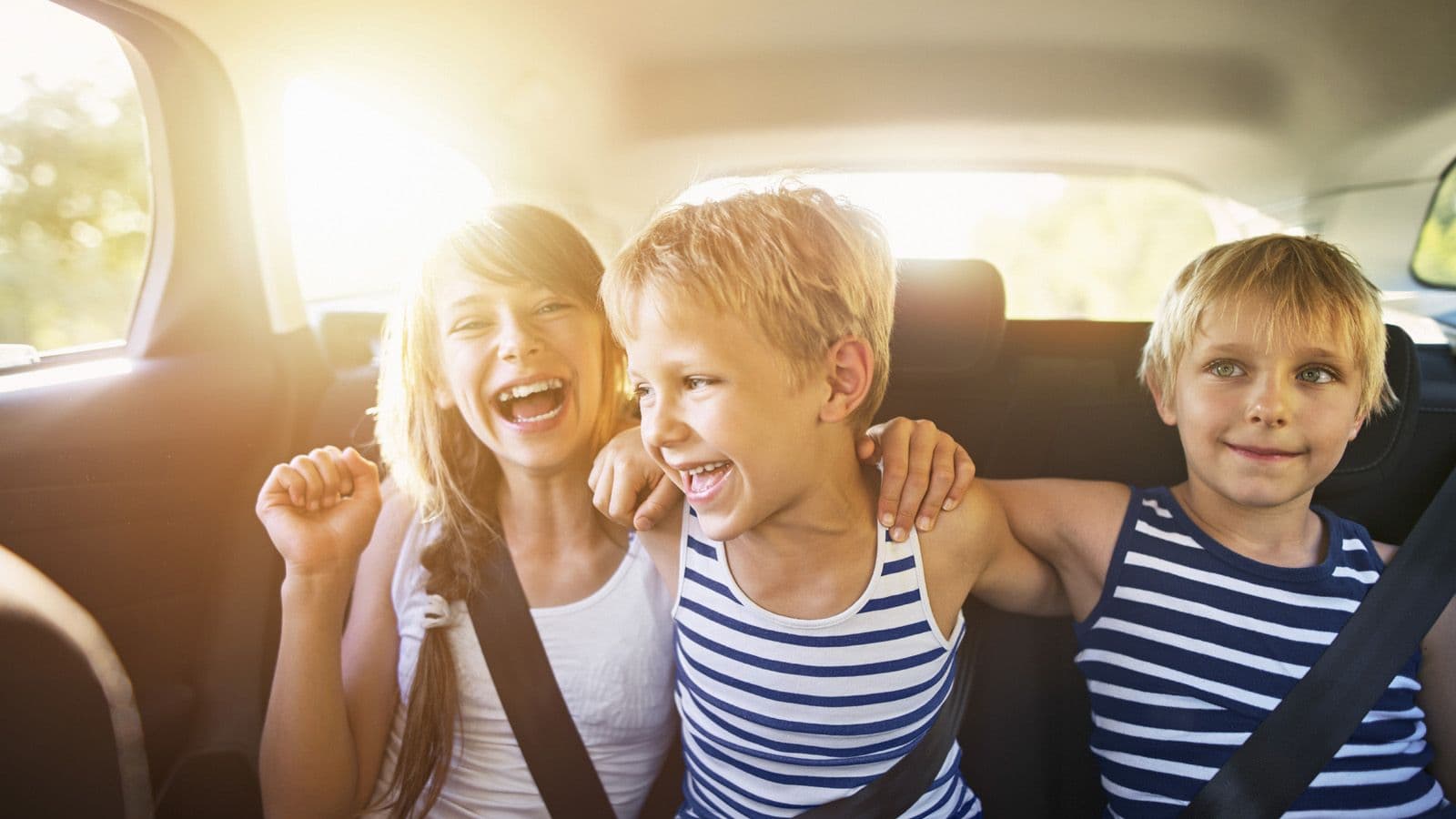 3 glade børn på bagsædet af en bil