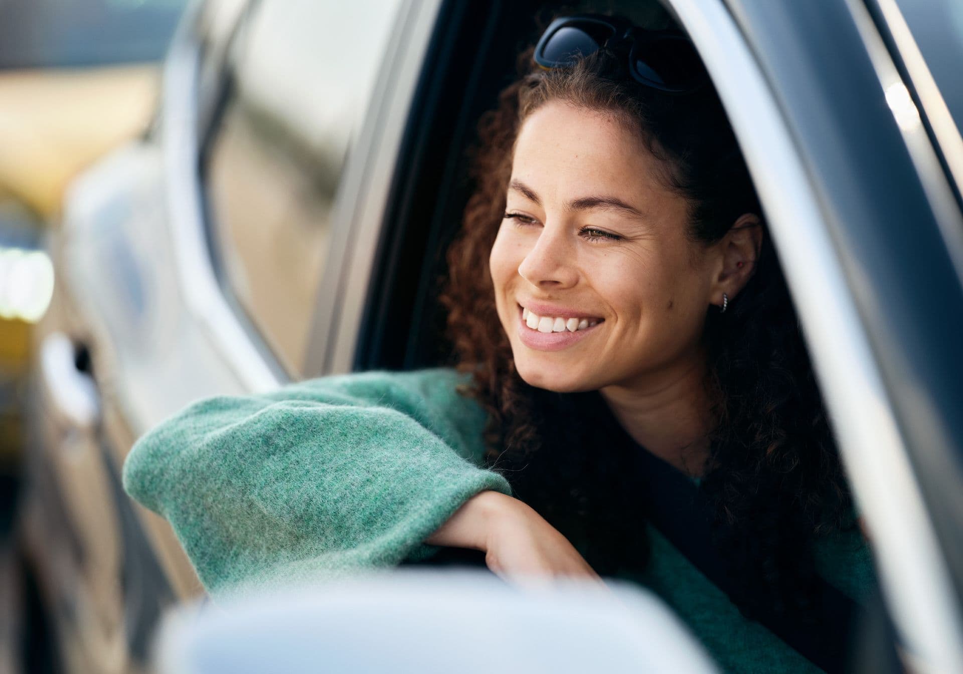 Smiling woman sitting in her car with the window down